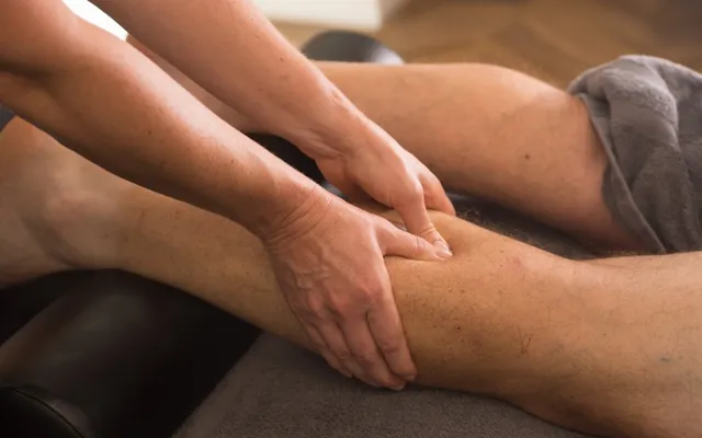 Firm thumb and hand pressure applied to a client's calf during a deep tissue technique